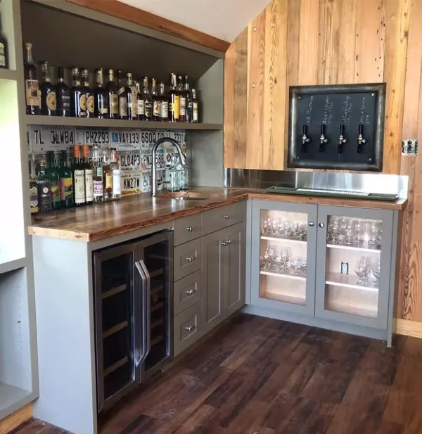 Built-in home bar with glass front cabinets and a wood countertop