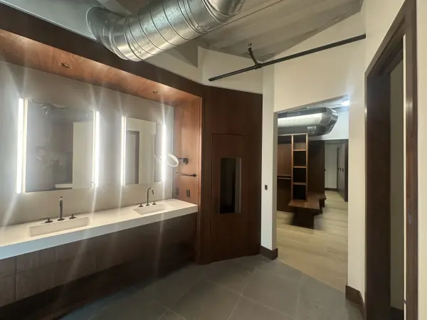 Walnut custom bathroom vanity below a backlit mirror