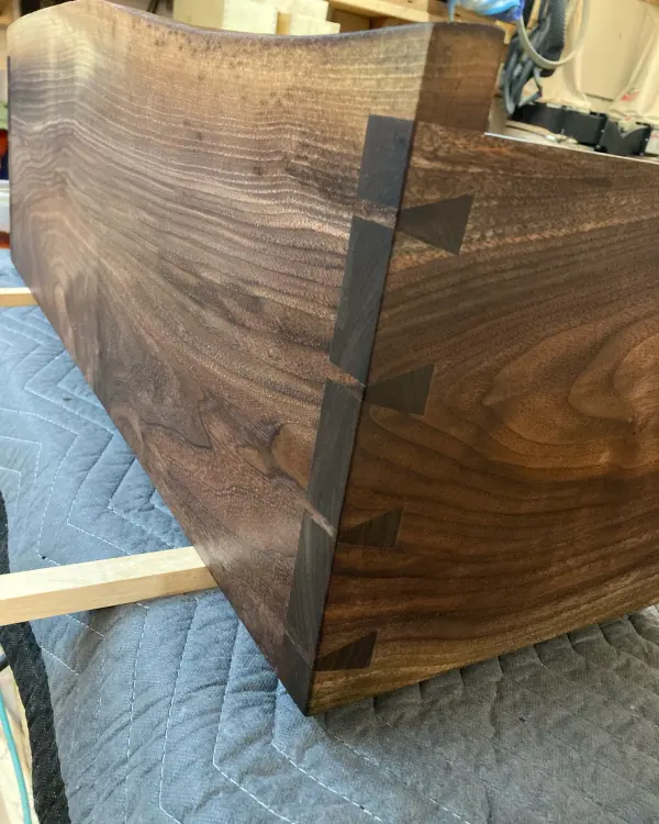 Exposed dovetail joint on a shaped walnut panel