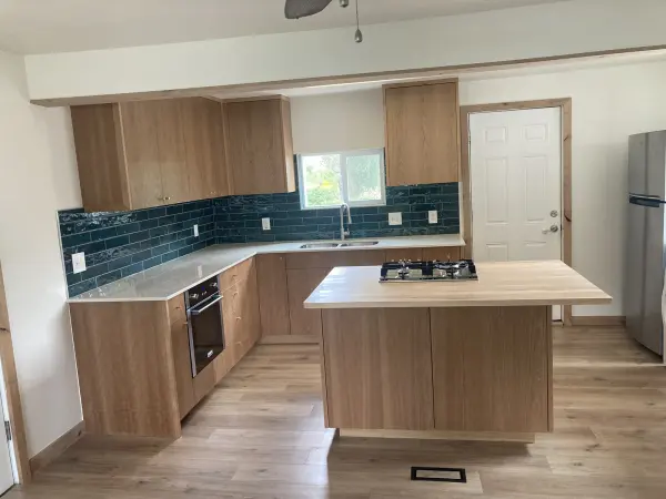 White oak flat panel kitchen cabinets with a teal tile backsplash