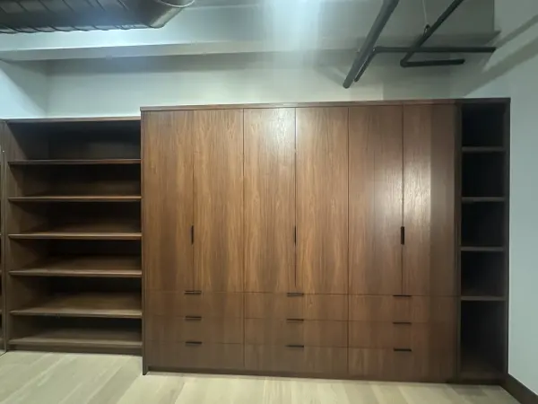 Built-in walnut wardrobe with flanking open shelves and drawers below