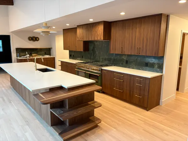 Walnut kitchen island with a sculptural floating shelf end and a full range beyond