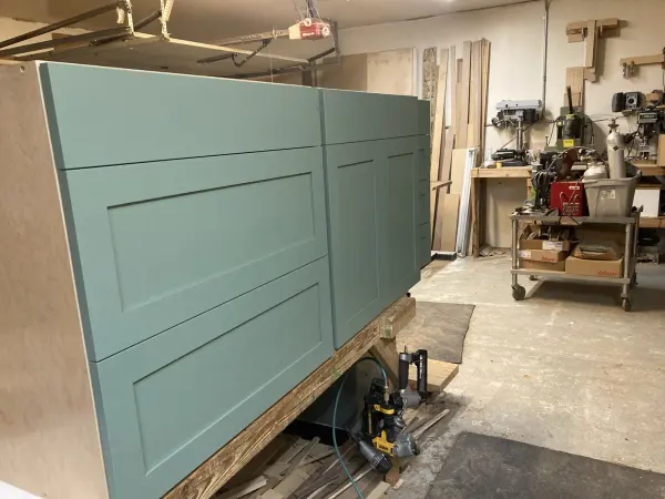 Shaker style painted teal kitchen cabinets, staged in the shop before install